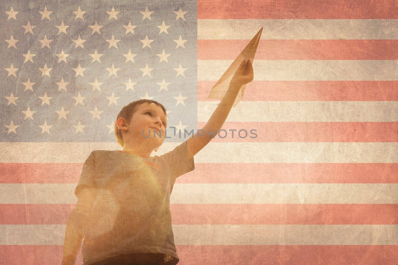 Little boy launches a paper plane into the air on the flag of america background. Child launches a paper plane with pride.