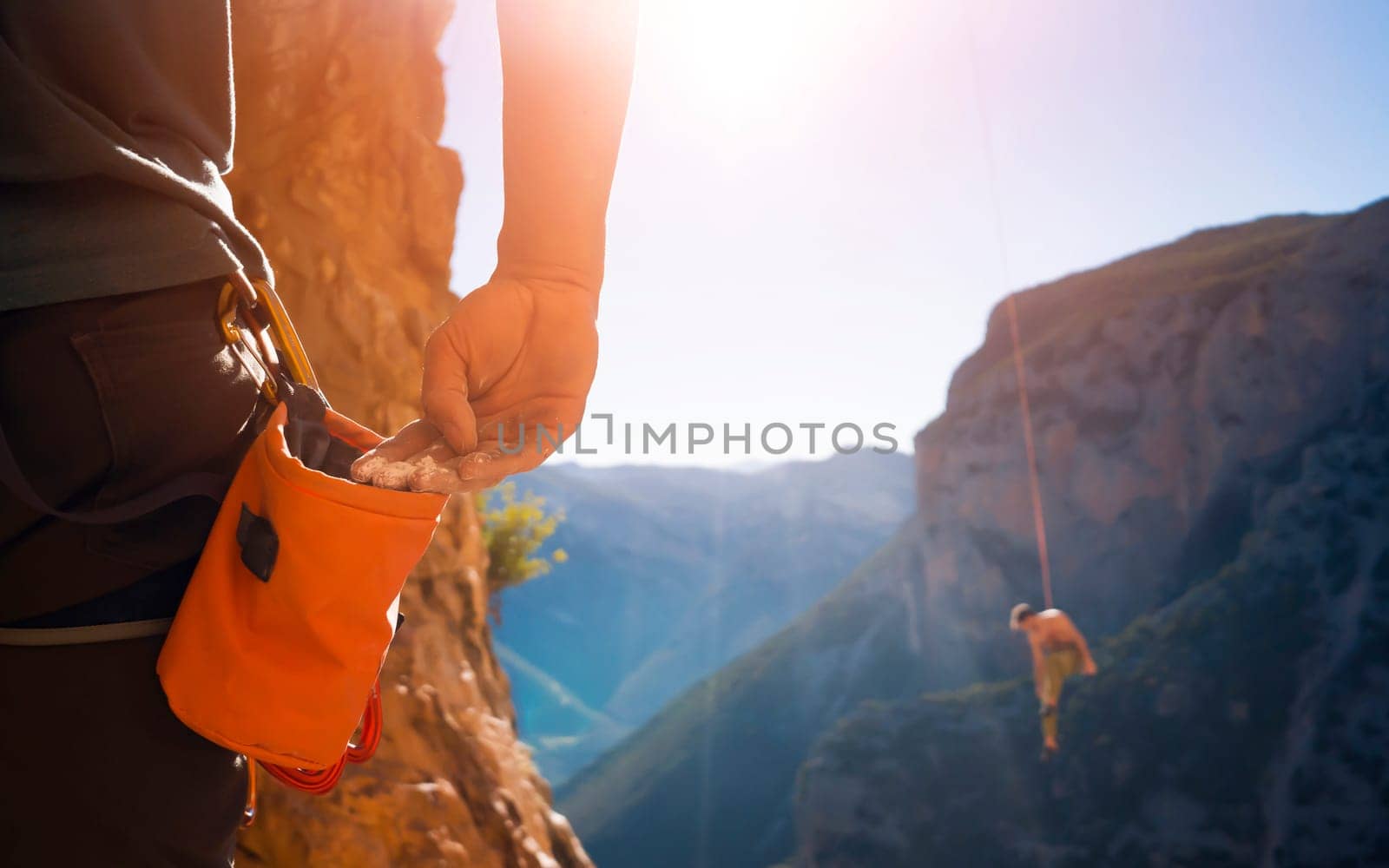 Male hand with magnesia powder close-up, against the background of beautiful mountains, the hand of climber who prepares for training outdoors, a man climbs in Twin Caves, Greece on a sunny day.