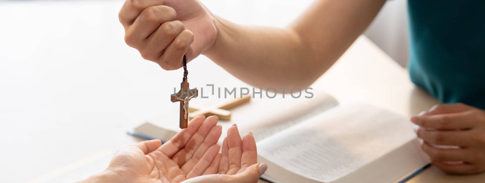 Close-up women prayer deliver wooden cross to young believer. Burgeoning. by biancoblue