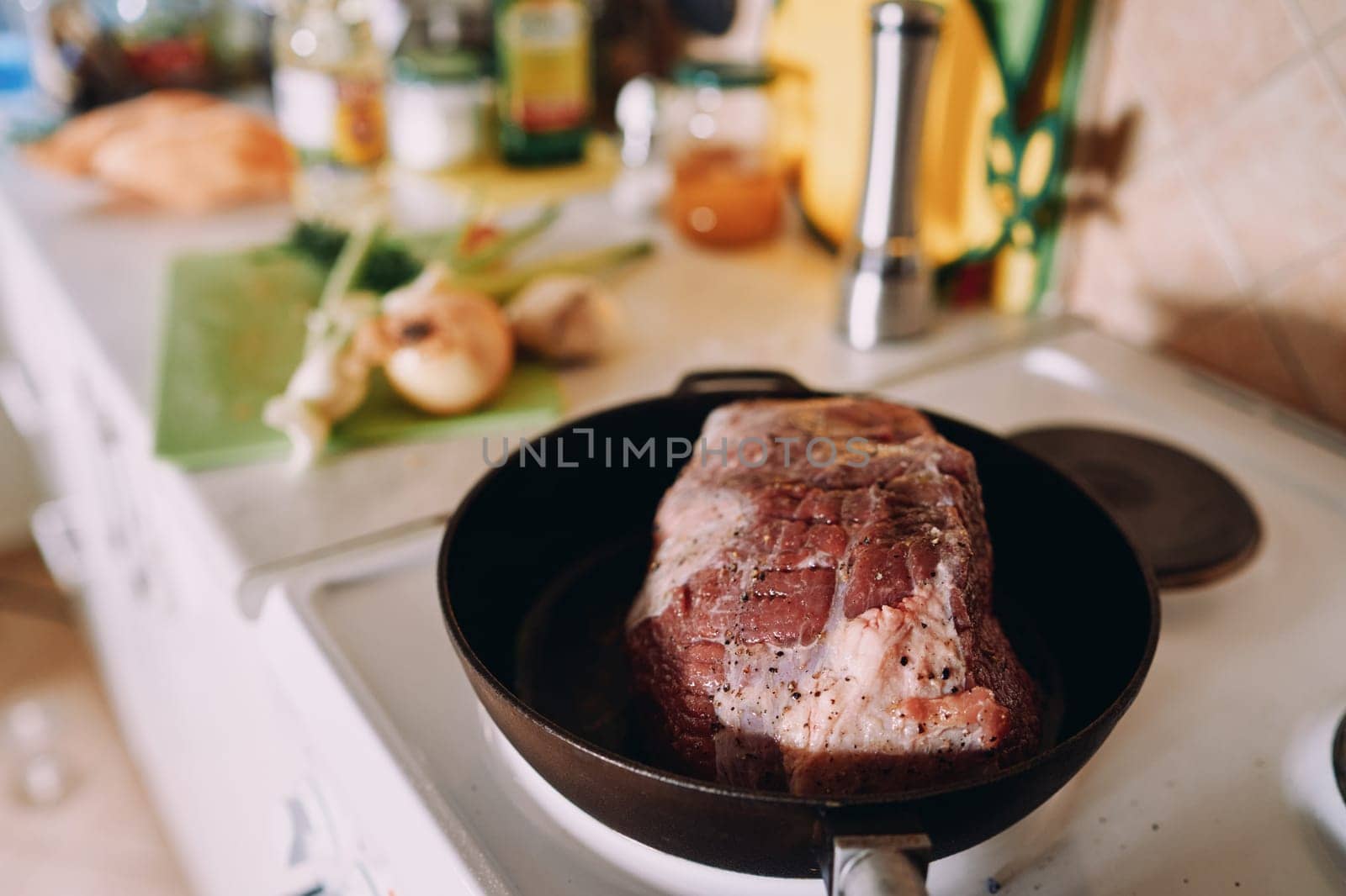 Raw piece of meat with spices is stewed in a frying pan on the stove. High quality photo