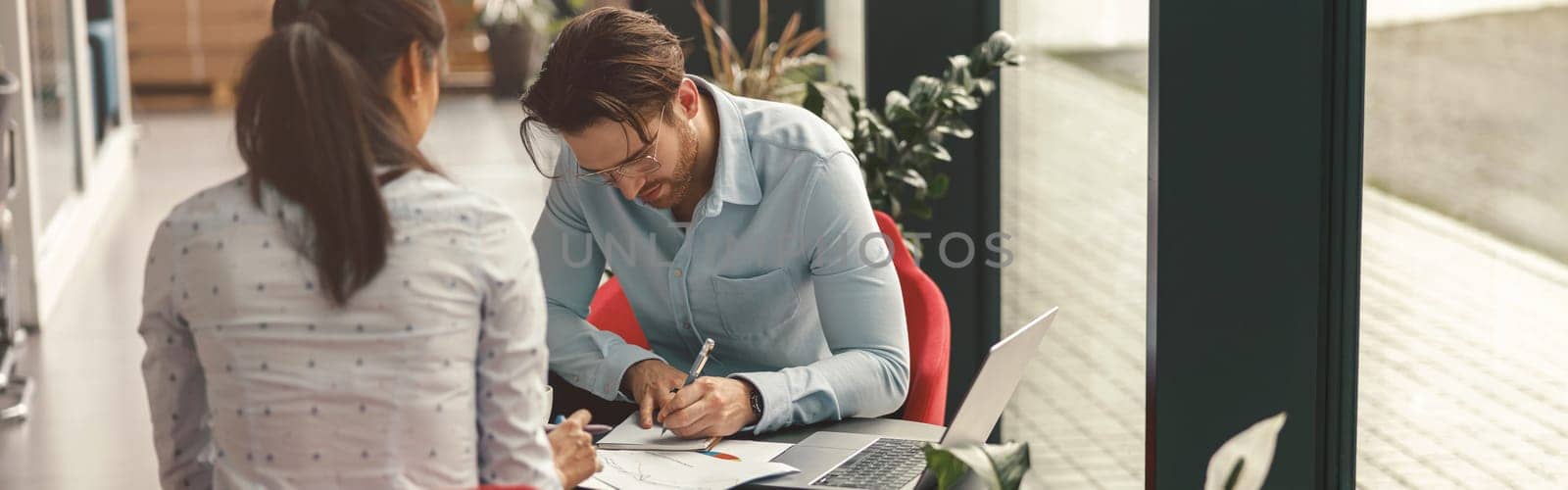 Two business colleagues working with documents together sitting in office.High quality photo