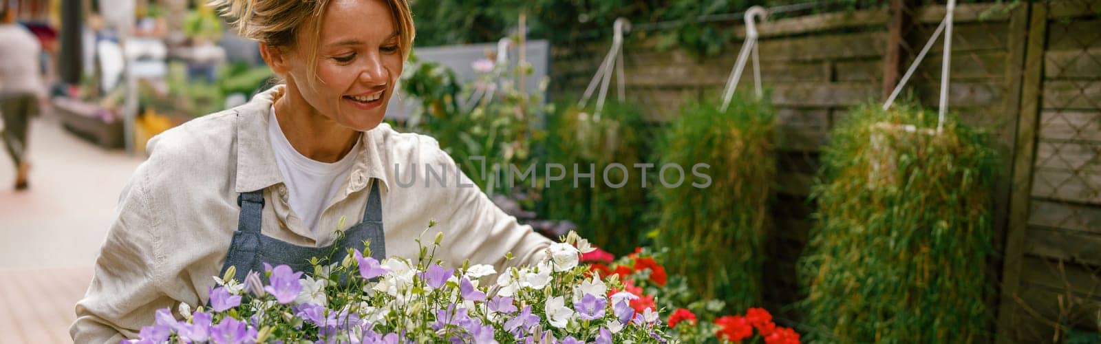 Female florist taking care of houseplant in flower shop. Plant care concept. High quality photo