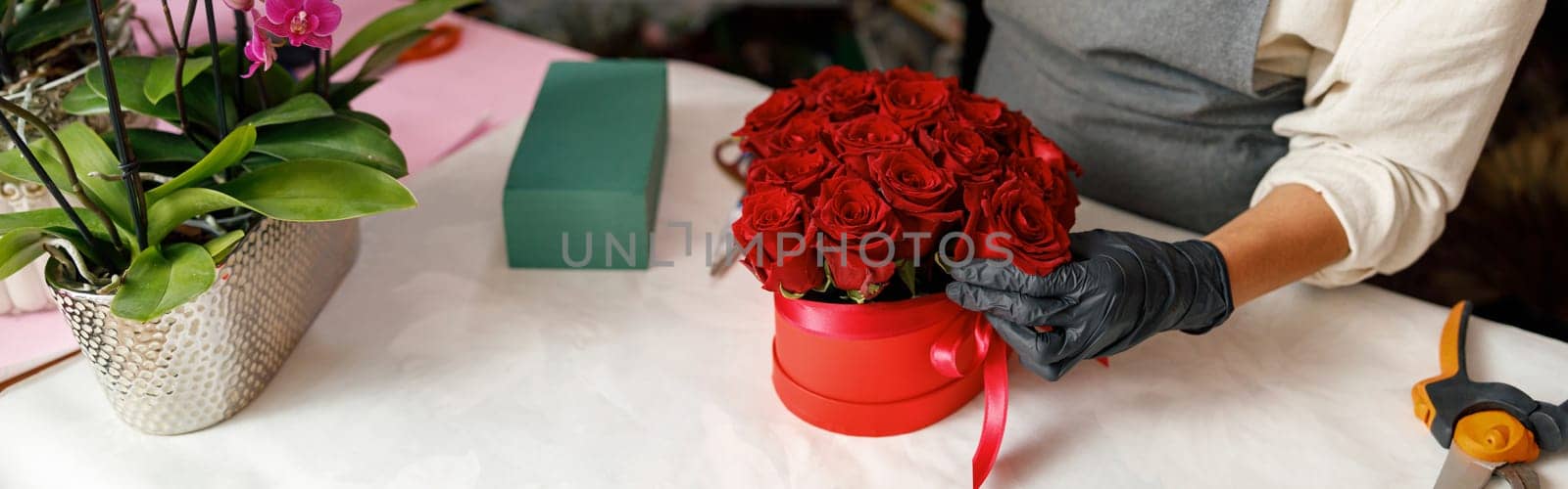 Close up of florist in flower shop make roses compositions for holiday. Family flower's business by Yaroslav_astakhov