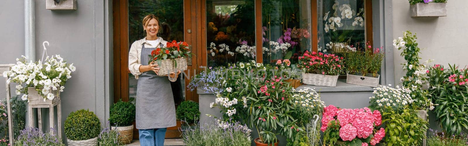 Woman florist small business owner standing in floral store and waiting for client with houseplant