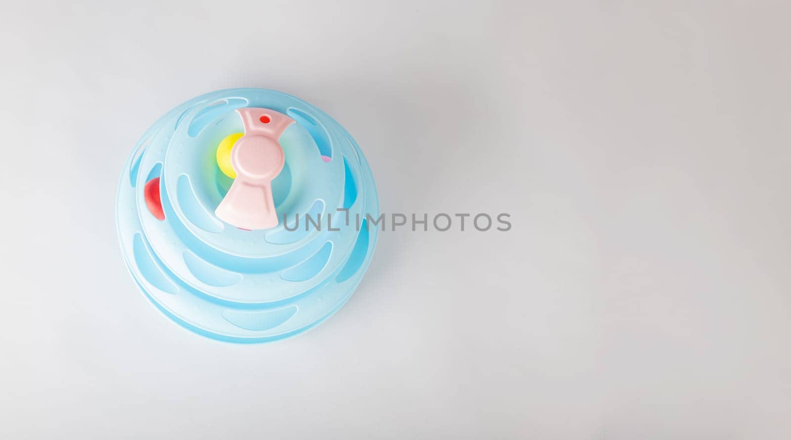 A playful cat engages with a blue tower toy on an isolated white background, featuring a circular turntable and a gripping moving ball. Witness feline intelligence and hunter instincts in action. by Sorapop