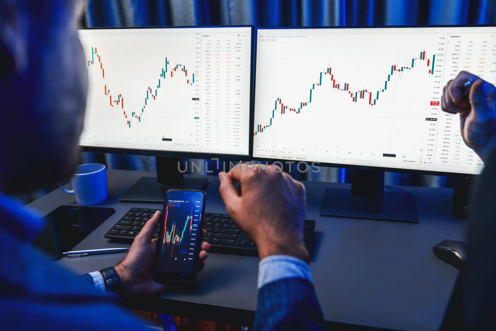 Two stock exchange traders researching data on smartphone and laptop screen server of dynamic digital currency. Investors analyzing market stock at decorative neon blue-light of workplace. Sellable.