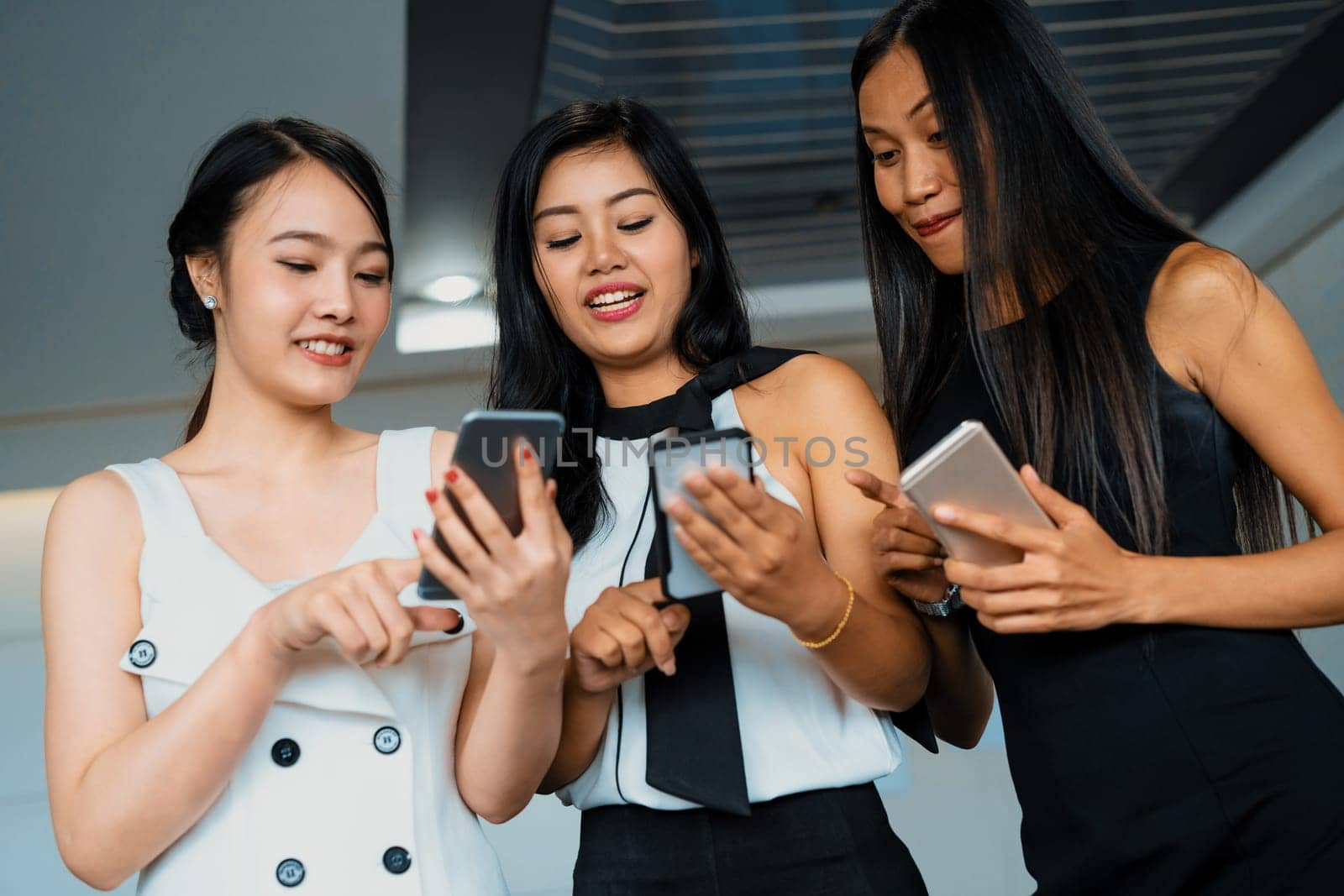 Three women friends having conversation while looking at mobile phone in their hands. Concept of social media, gossip news and online shopping. uds