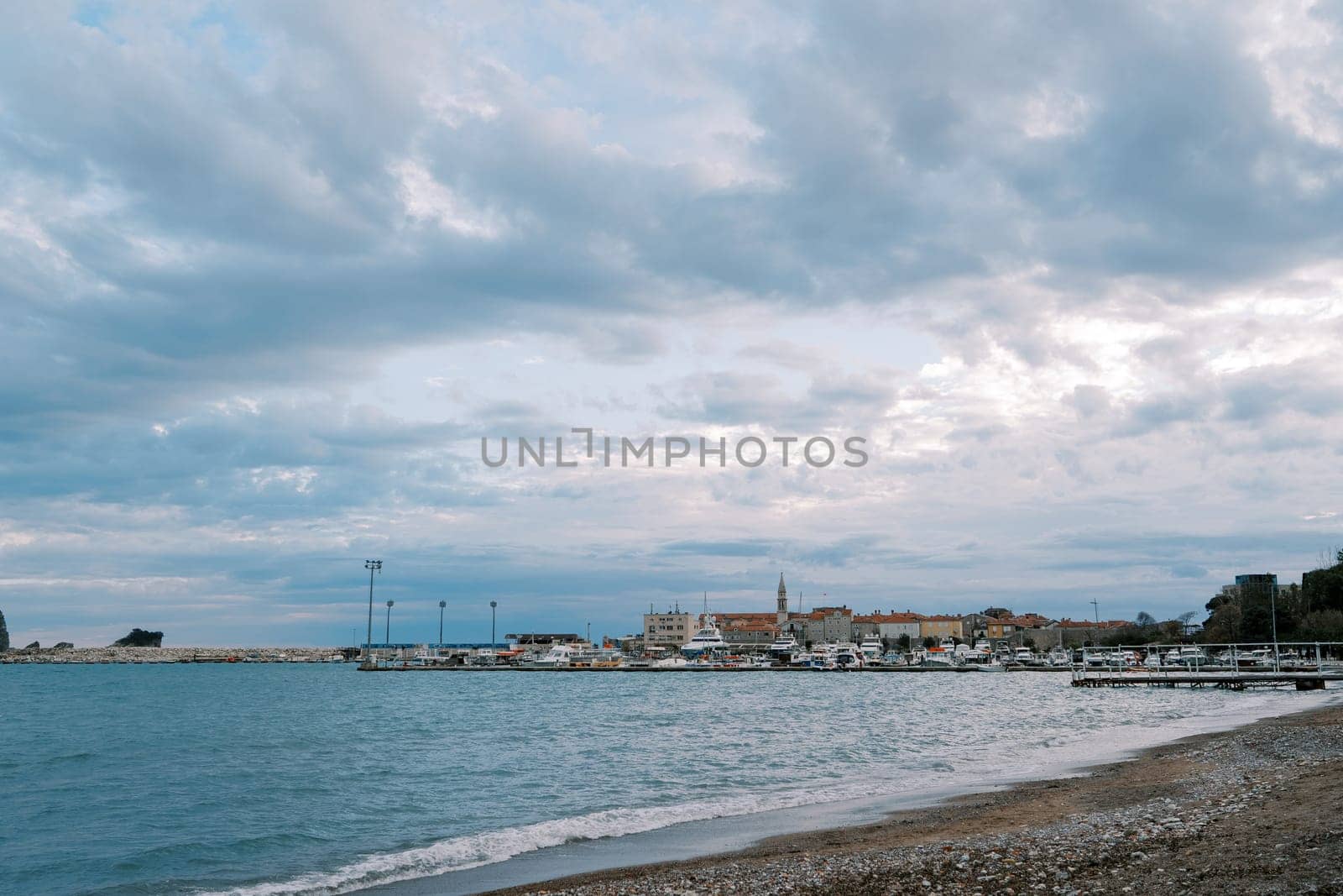 Resort town with a marina on the seashore against a cloudy sky by Nadtochiy