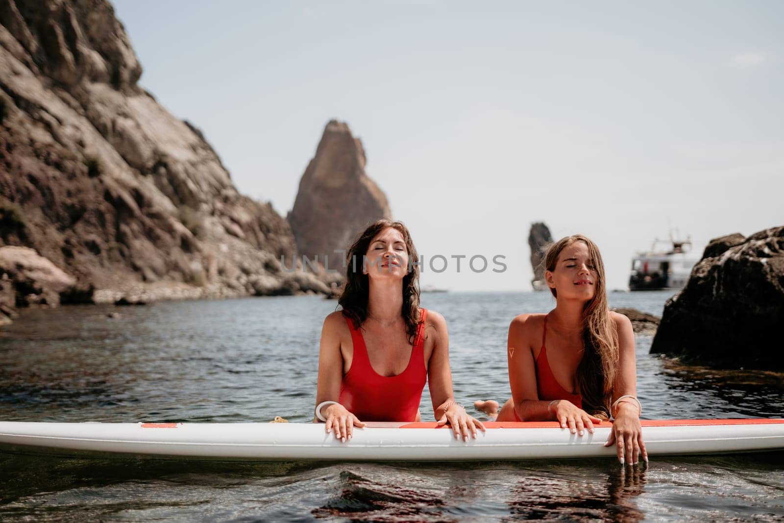 Woman sup yoga. Middle age sporty woman practising yoga pilates on paddle sup surfboard. Female stretching doing workout on sea water. Modern individual hipster outdoor summer sport activity