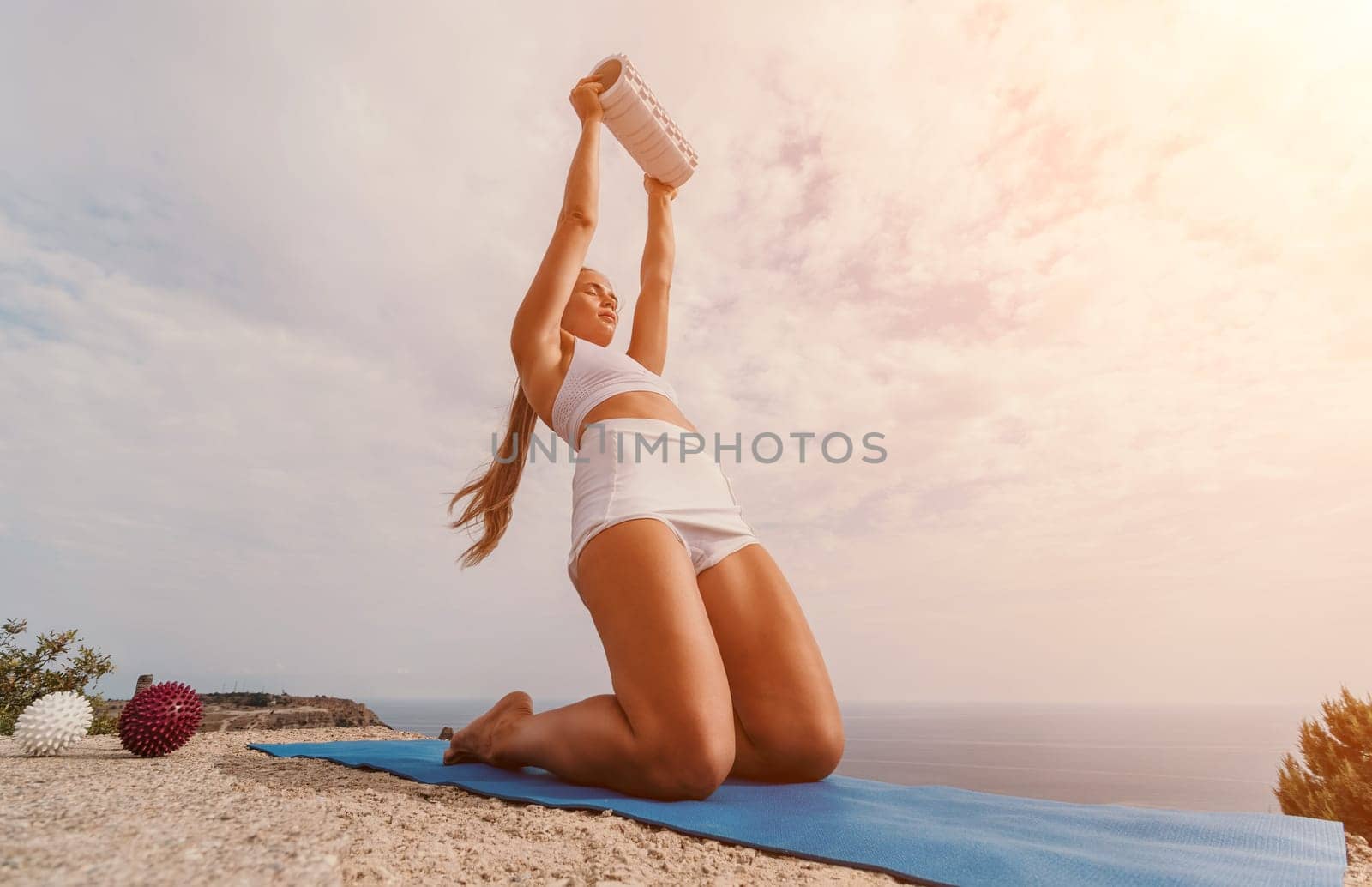 Woman sea pilates. Sporty, middle-aged woman practicing pilates in park near the sea. trains on a yoga mat and exudes a happy and active demeanor. healthy lifestyle through exercise and meditation. by panophotograph