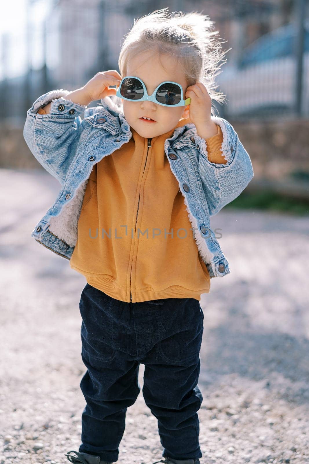 Little girl trying on sunglasses upside down. High quality photo
