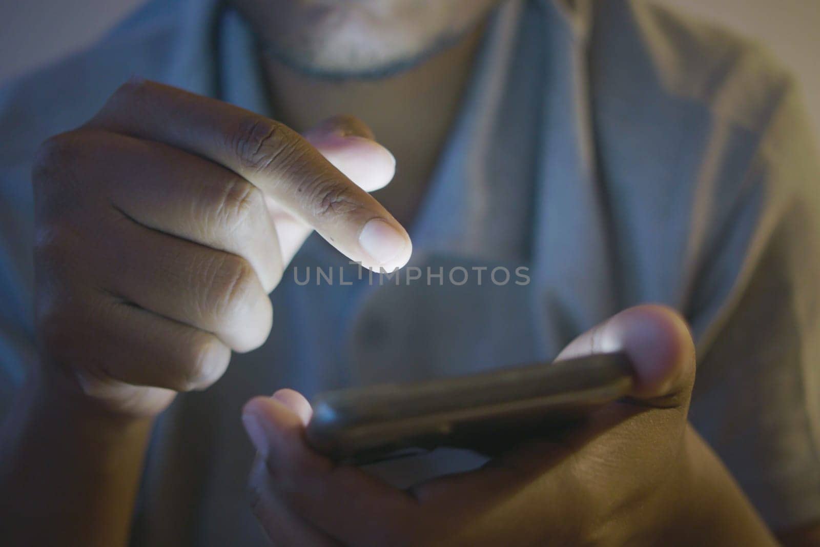 Close up of man's hand using smart phone at night .