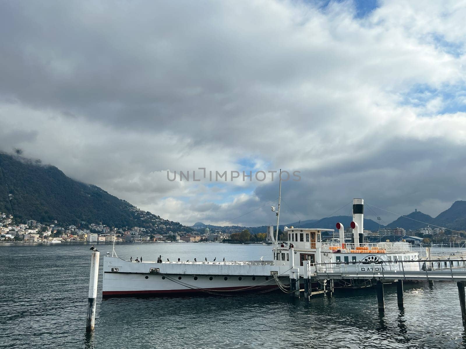 Small ship is moored at the pier on Lake Como. Italy. High quality photo