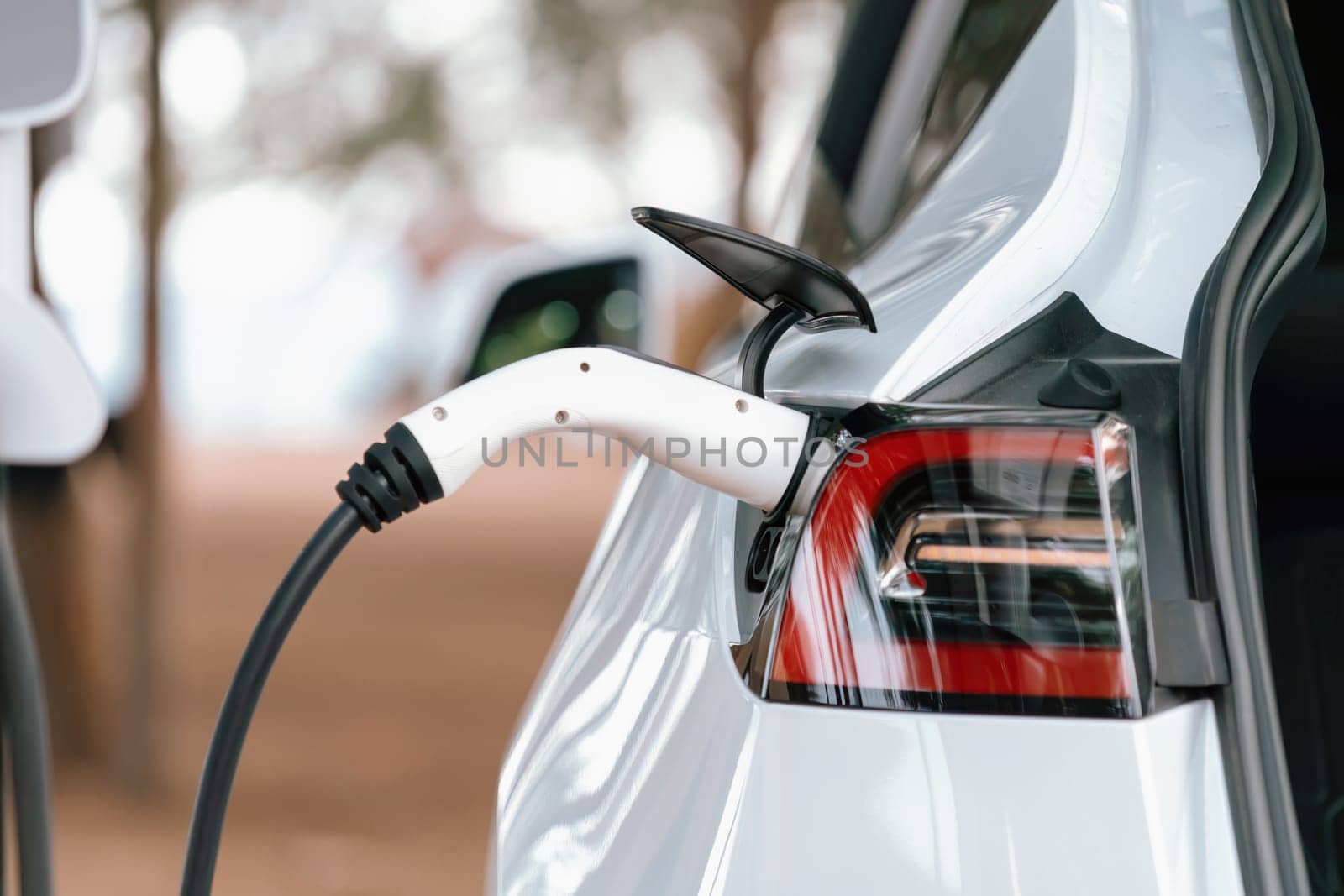 Closeup EV charger handle plugged in or connect to electric car, recharging EV car battery with alternative and sustainable energy with zero CO2 emission for clean environment. Perpetual