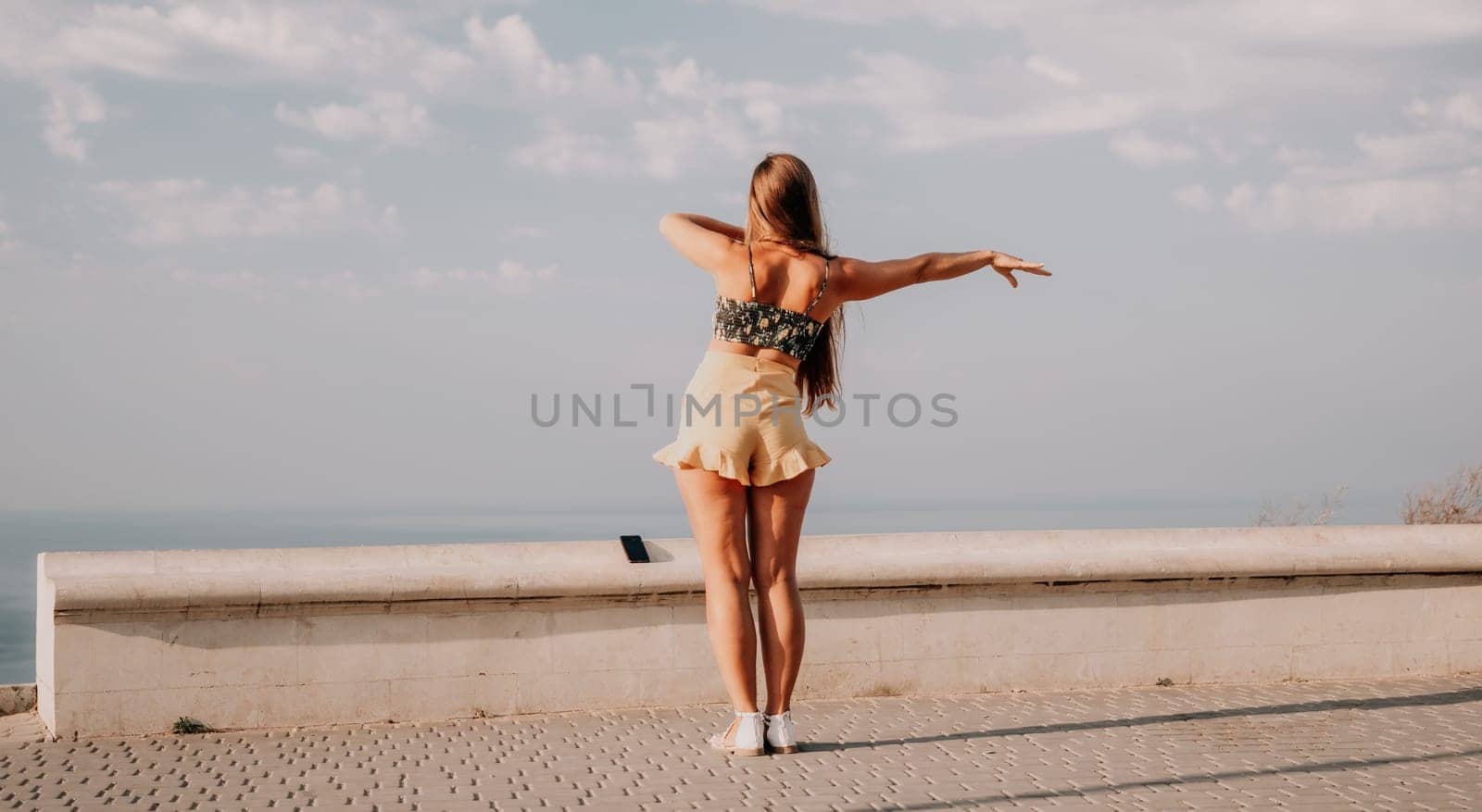 silhouette of a happy woman who dances, spins and raises her hands to the sky. A woman is enjoying a beautiful summer day.