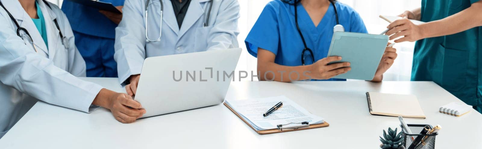 Professional various team of medical working and planning medical treatment at hospital table together. Teamwork lead to successful illness and sickness treatment. Panorama Rigid