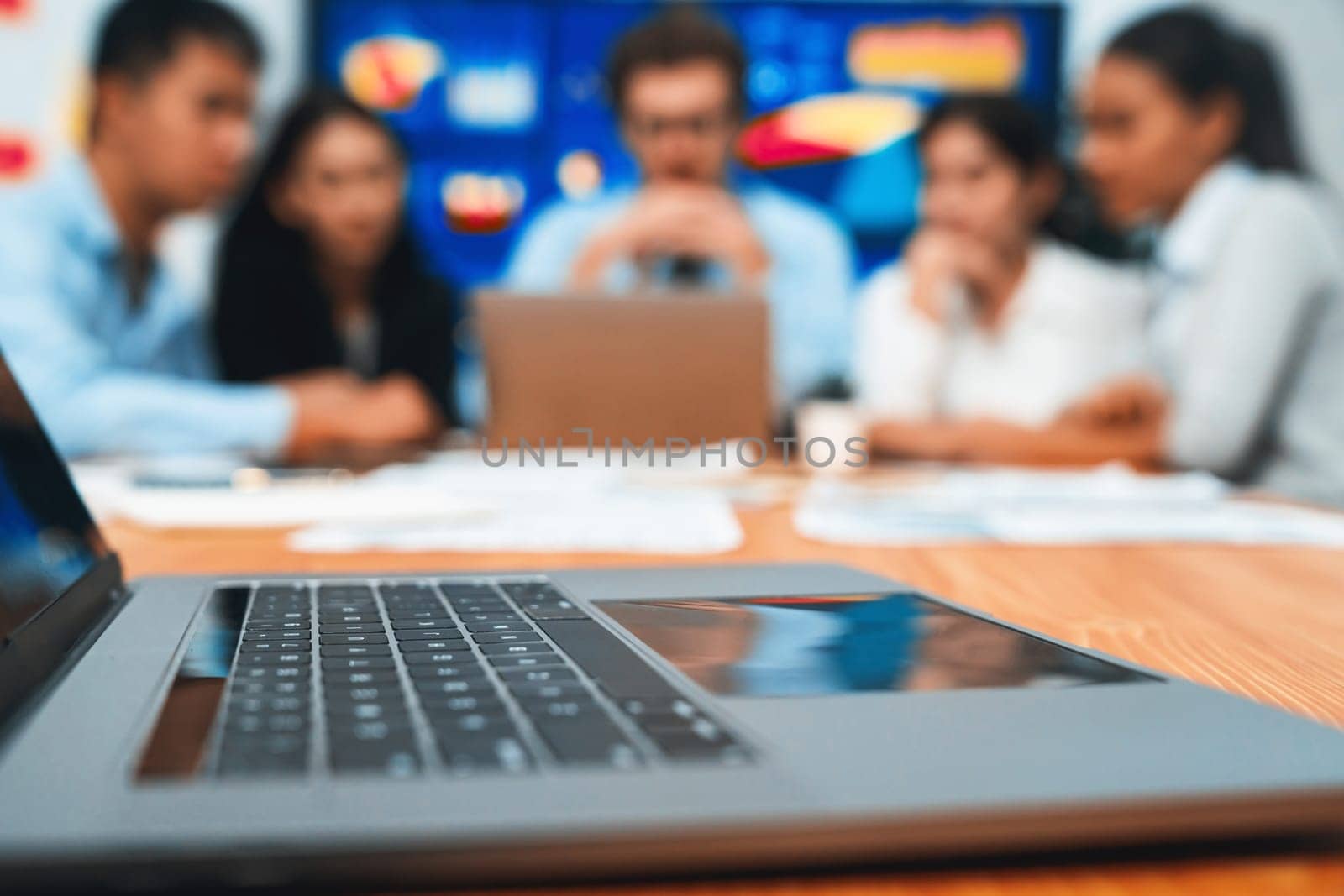 Closeup focused laptop with blurred background of business people using laptop computer to analyze financial data or data analysis display on screen background. Meticulous