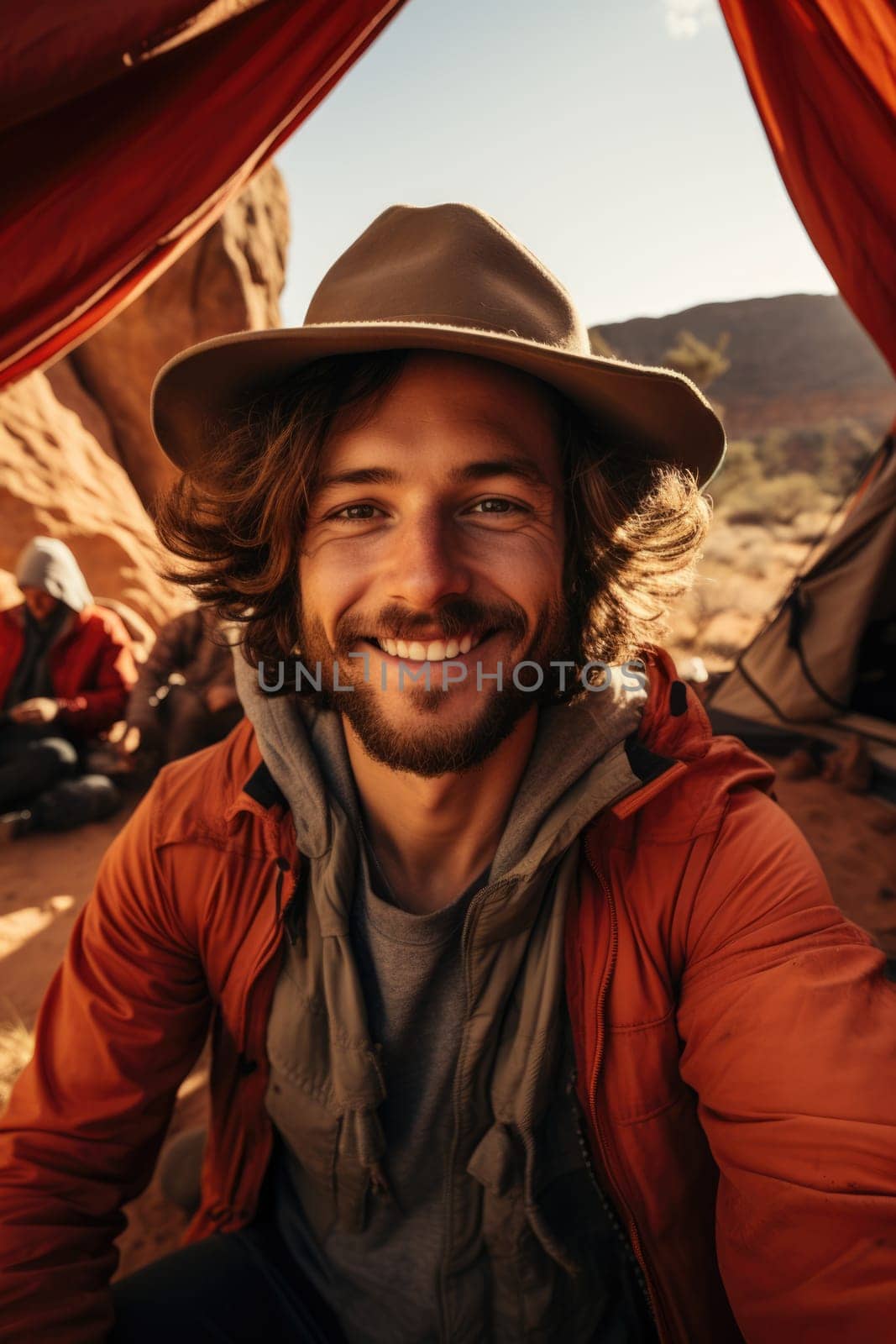 Happy hiker man with hat making selfie photo portrait background tent mountain. Concept travel blogger, adventure life trip. AI Generated