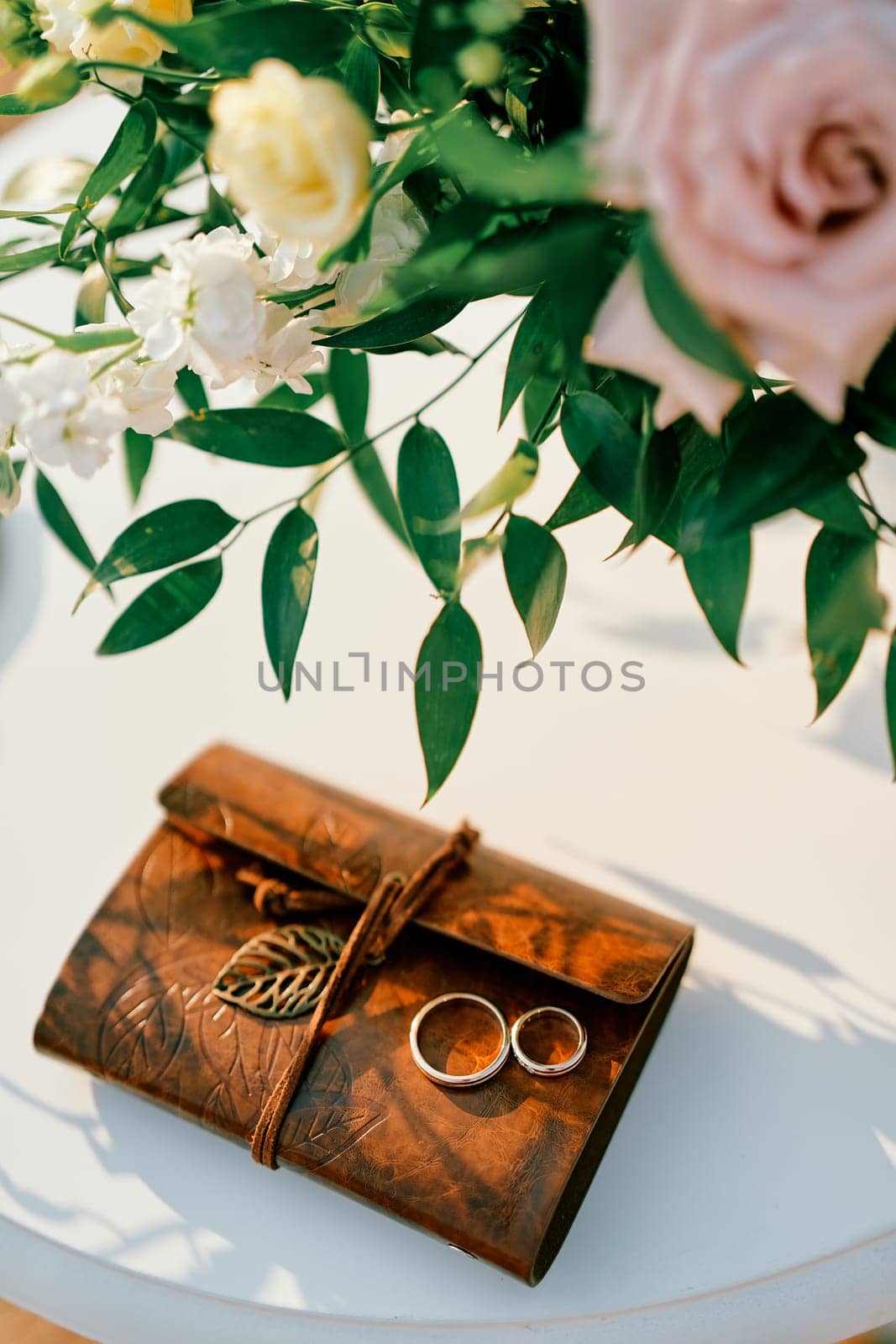 Wedding rings lie on a notepad on the table near the bride's bouquet. High quality photo