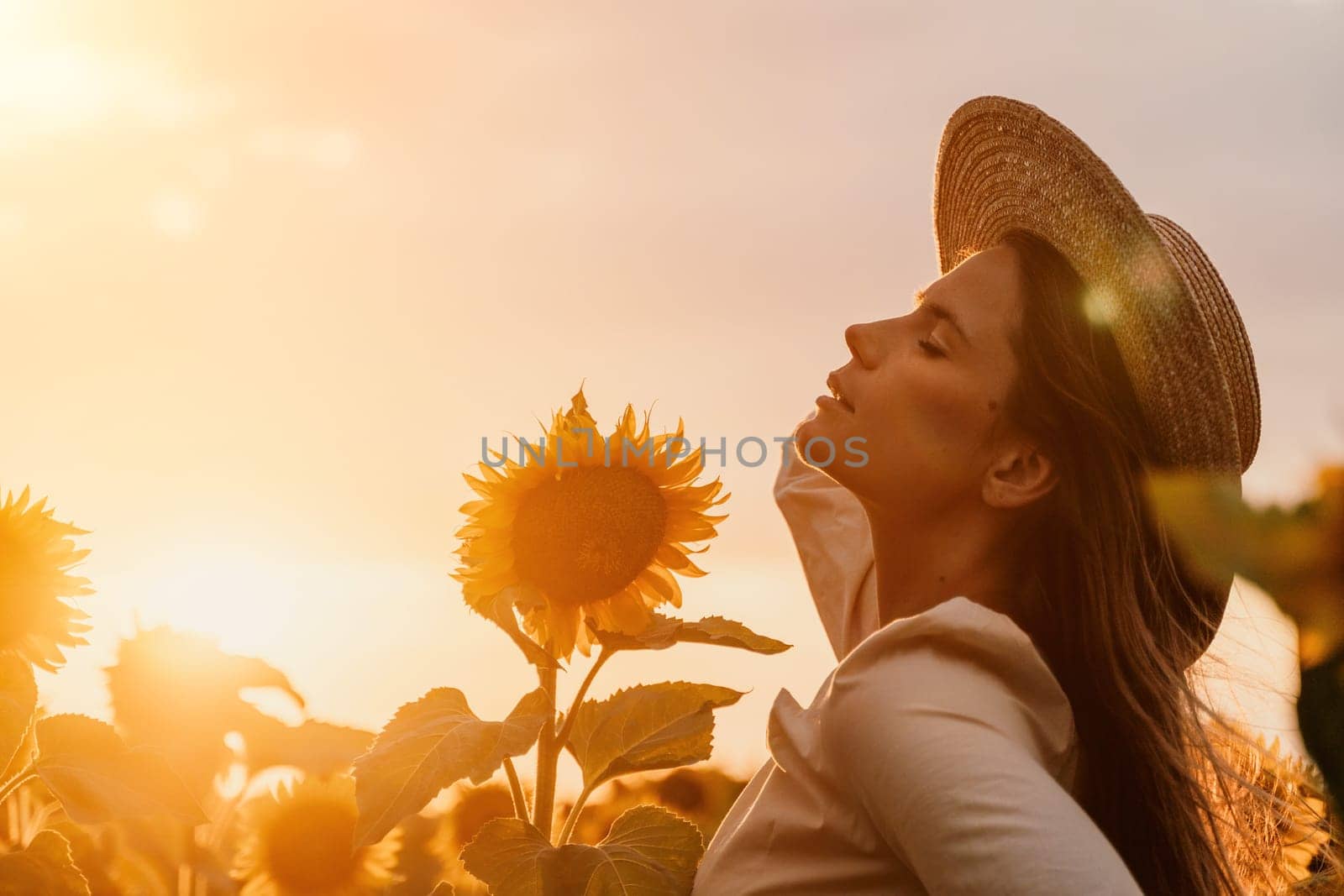 Woman in Sunflower Field: Happy girl in a straw hat posing in a vast field of sunflowers at sunset, enjoy taking picture outdoors for memories. Summer time. by panophotograph