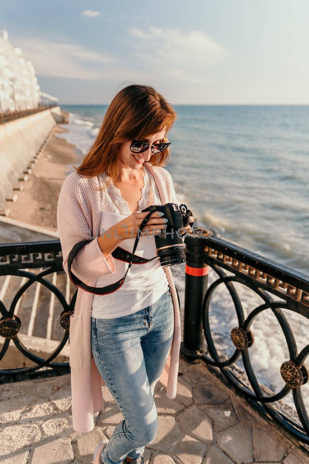 Woman summer travel sea. Happy tourist enjoy taking picture outdoors for memories. Carefree woman traveler posing on beach at sea on sunset, sharing travel adventure journey. Holiday vacation concept. by panophotograph