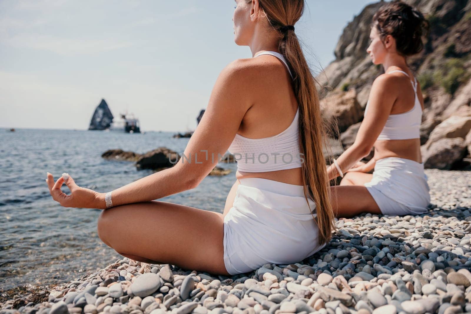 Woman sea yoga. Happy women meditating in yoga pose on the beach, ocean and rock mountains. Motivation and inspirational fit and exercising. Healthy lifestyle outdoors in nature, fitness concept. by panophotograph