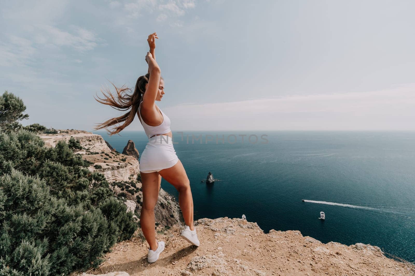 Middle aged well looking woman with black hair doing Pilates with the ring on the yoga mat near the sea on the pebble beach. Female fitness yoga concept. Healthy lifestyle, harmony and meditation.