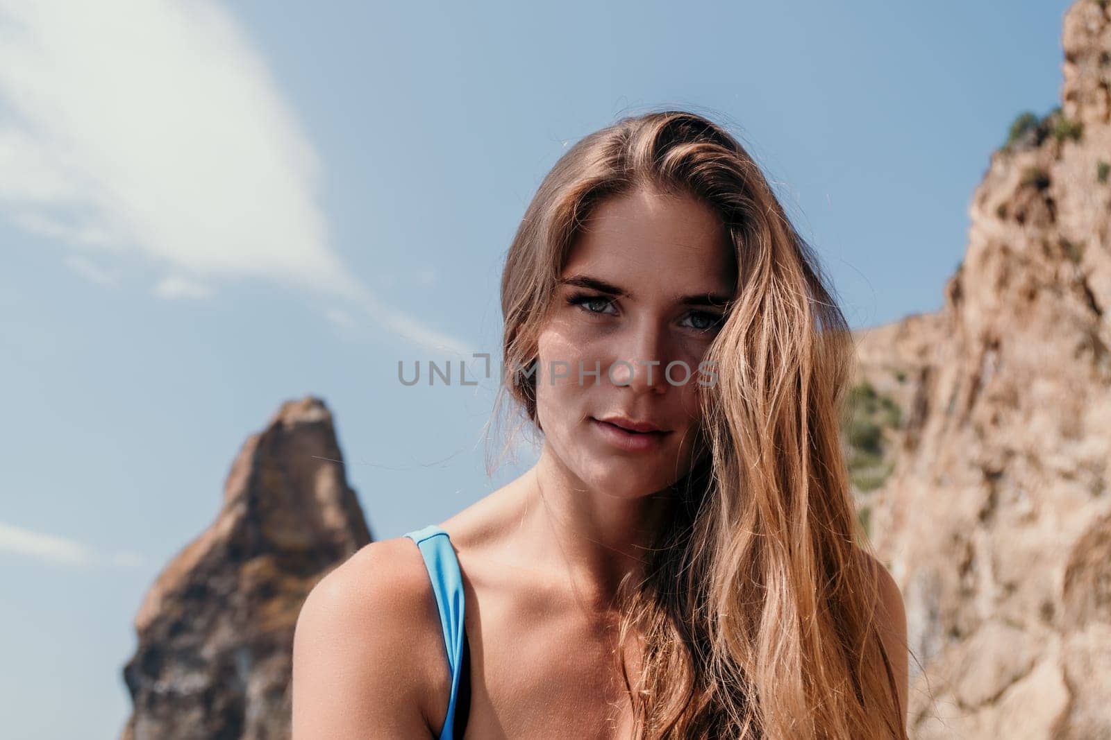 Woman travel sea. Young Happy woman in a long red dress posing on a beach near the sea on background of volcanic rocks, like in Iceland, sharing travel adventure journey