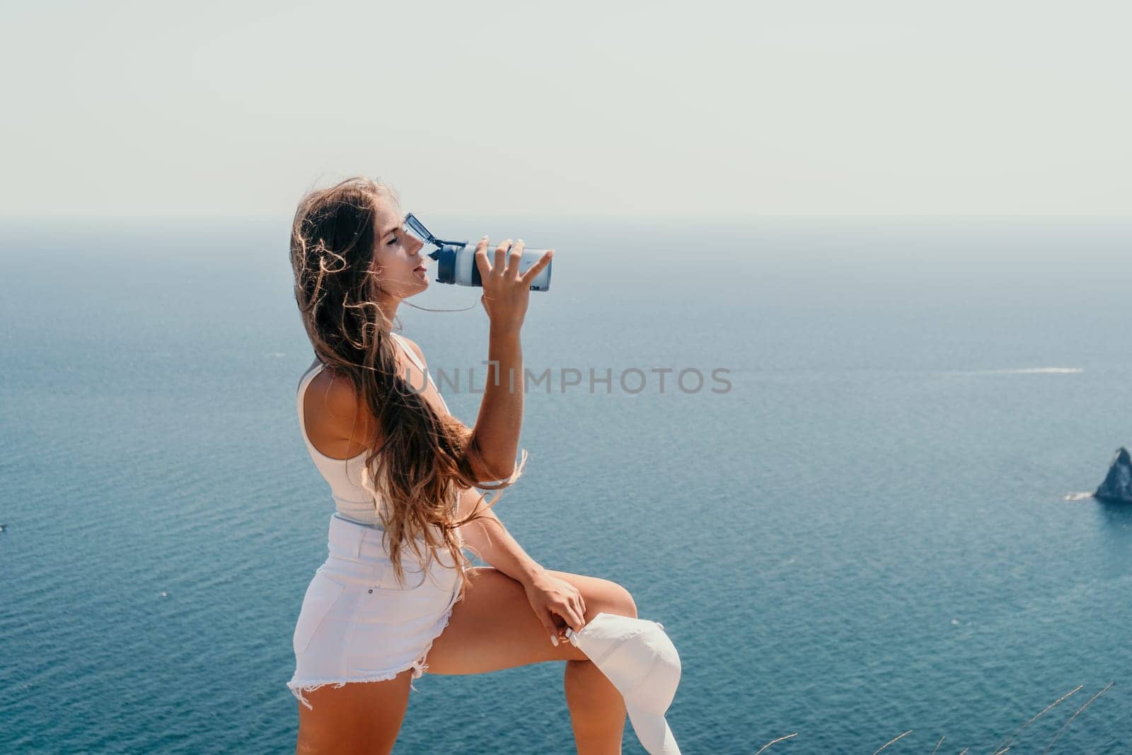 Woman travel sea. Young Happy woman in a long red dress posing on a beach near the sea on background of volcanic rocks, like in Iceland, sharing travel adventure journey