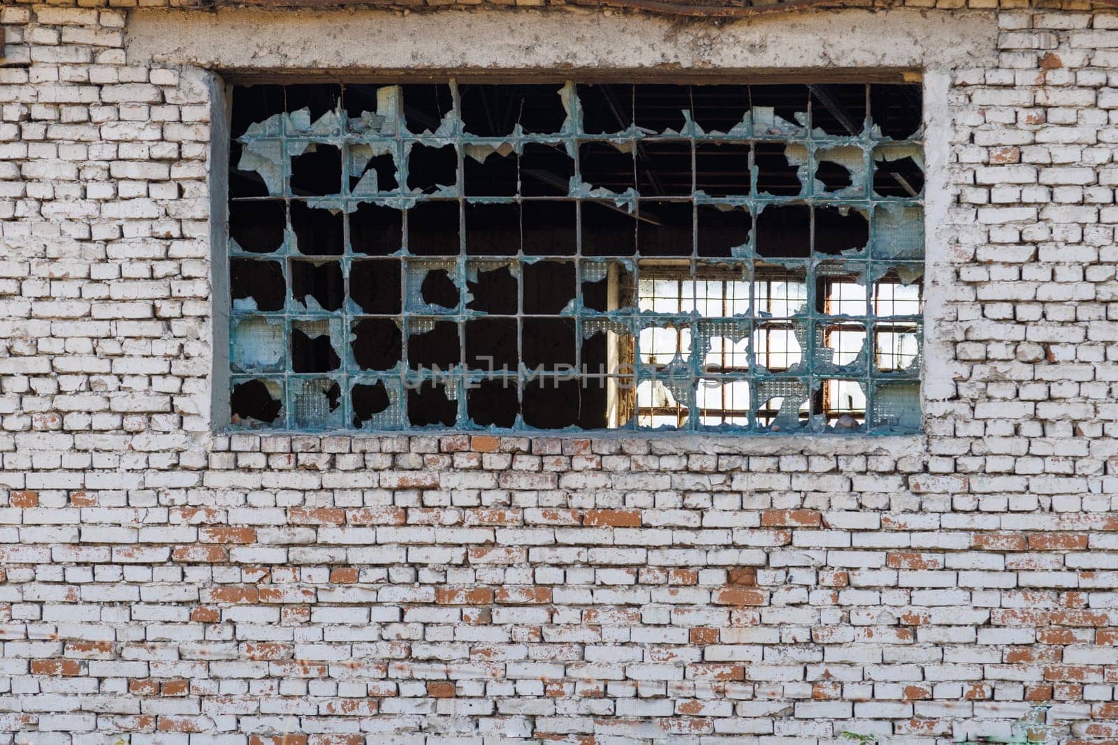 broken glass block window in white brick wall texture and background.