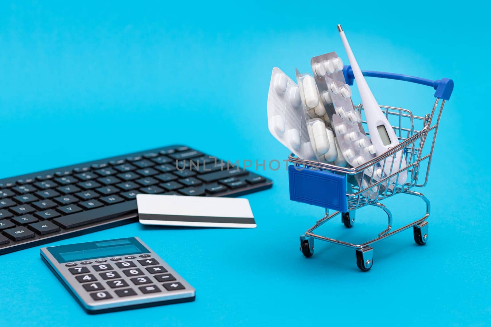 Ordering Medicines. Expensive Medicine and Inflation Concept: Pills and Capsules in a Shopping Cart on Blue Background. Global Pharmaceutical Industry and Big Pharma. Trade in Medicines