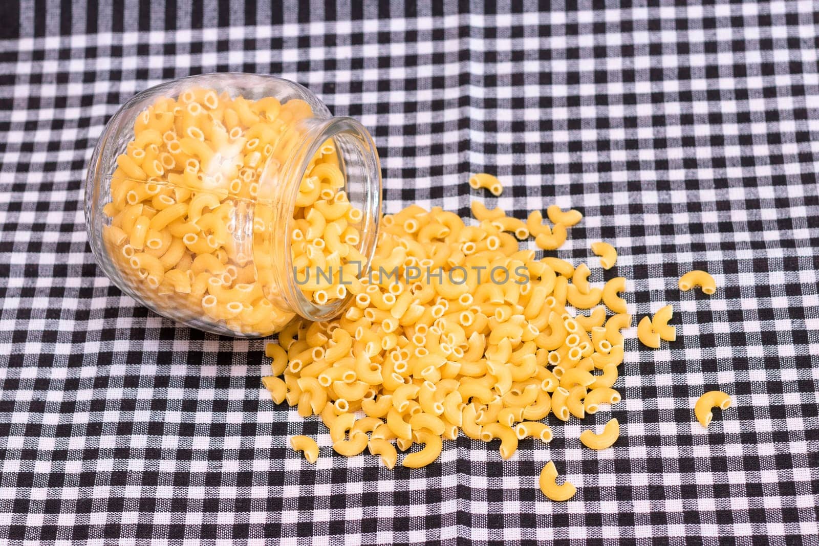 Scattered Uncooked Chifferi Rigati Pasta on Black Checkered Towel. Fat and Unhealthy Food. Classic Dry Macaroni. Italian Culture and Cuisine. Raw Pasta