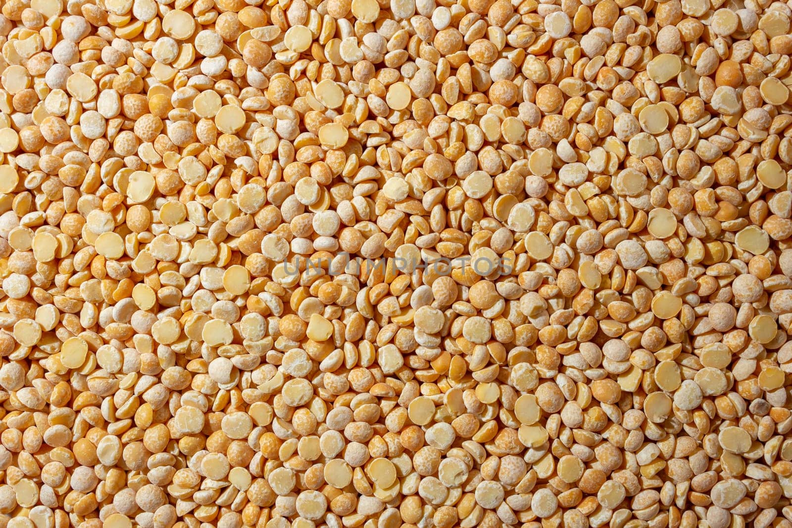 Uncooked Polished Split Peas Background. A Culinary Canvas of Dry Yellow Peas, Creating a Lively and Textured Background for Gourmet Cooking. Scattered Raw Polished Peas. Healthy Eating Ingredients