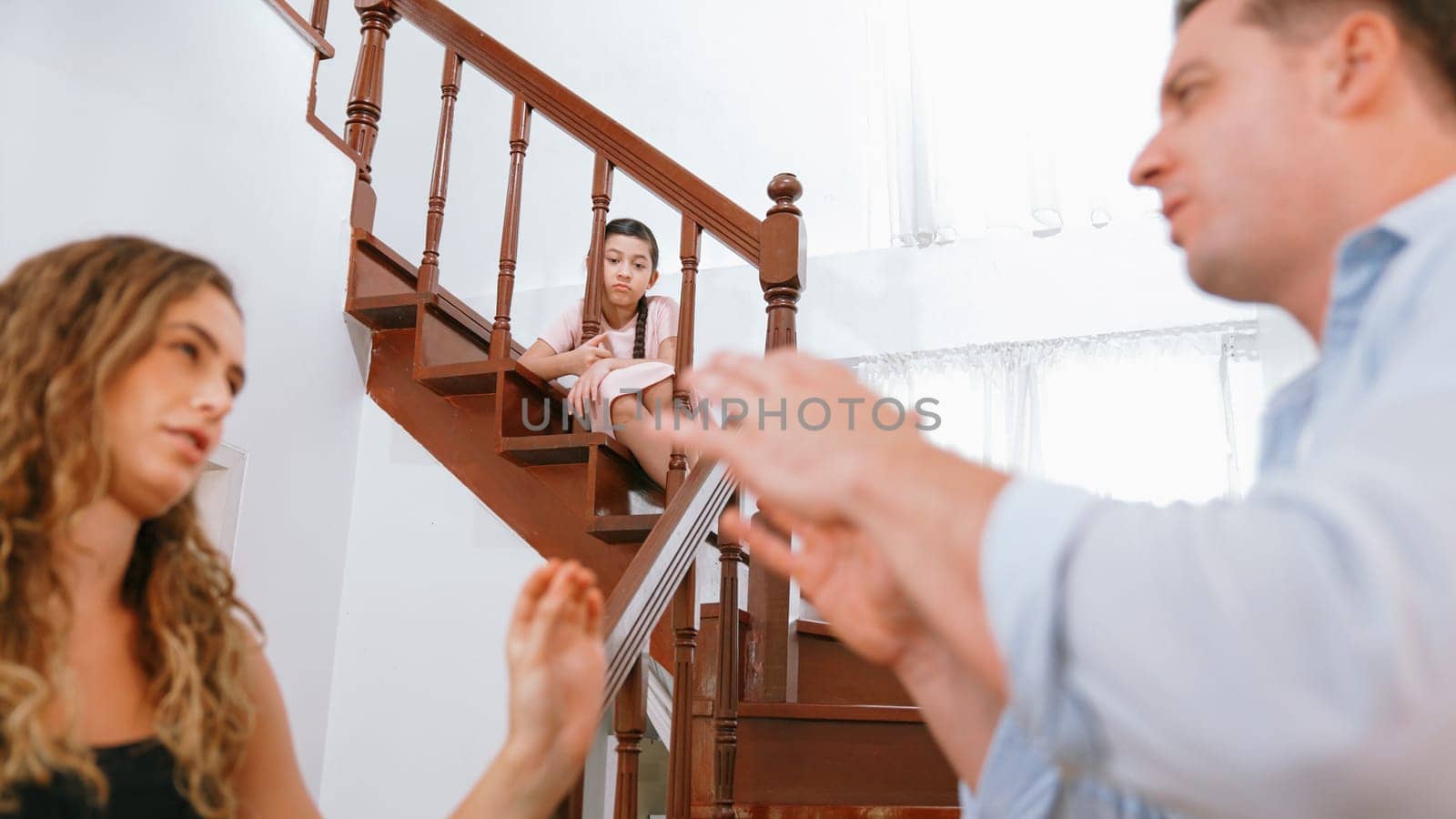 Stressed and unhappy young girl watch her parent arguing from the stair. Domestic violence at home and traumatic childhood develop to depression and anxiety. Unhealthy family concept. Synchronos