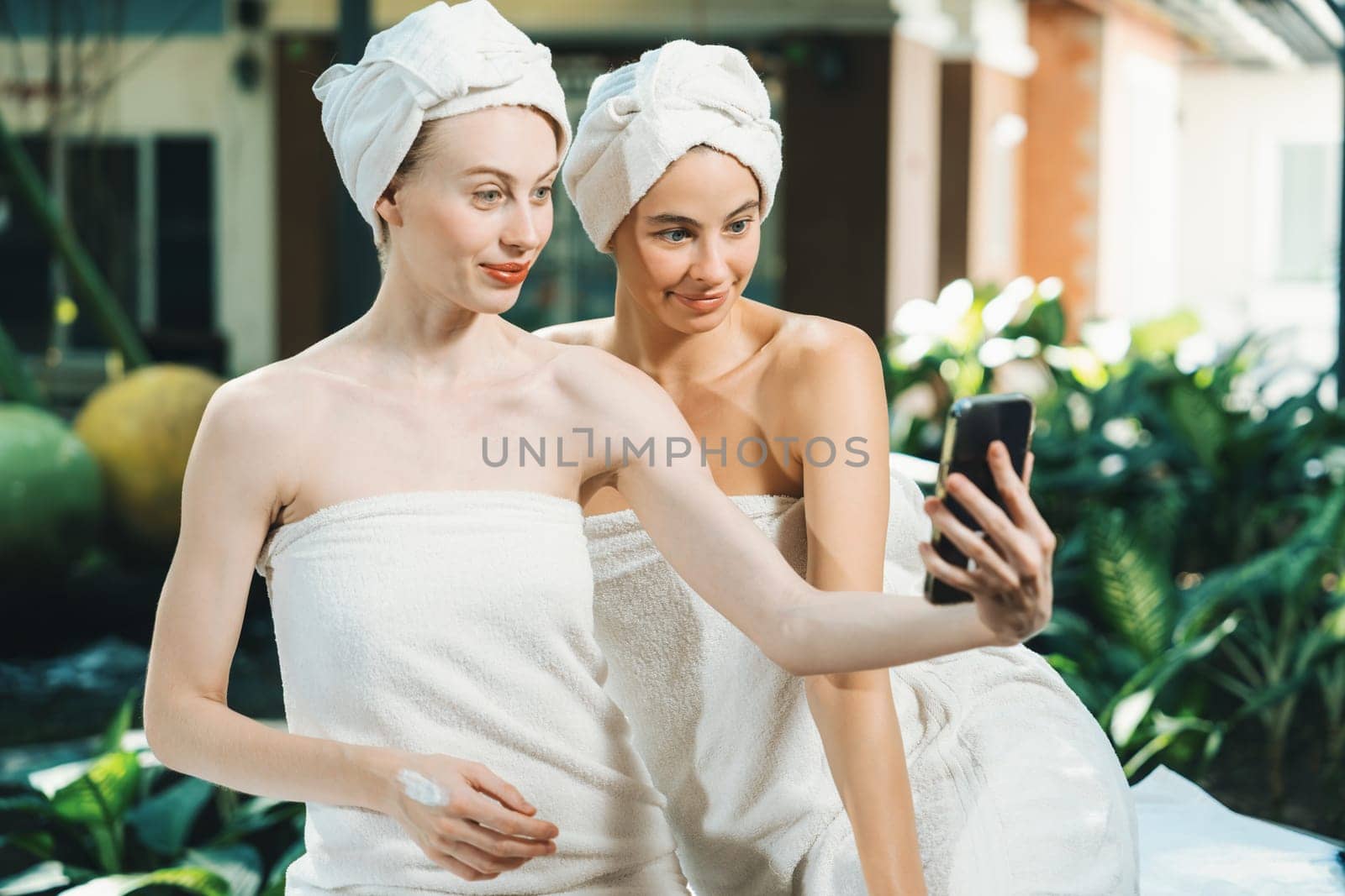Couple of beautiful women in white towel taking a photo at outdoor. Tranquility. by biancoblue