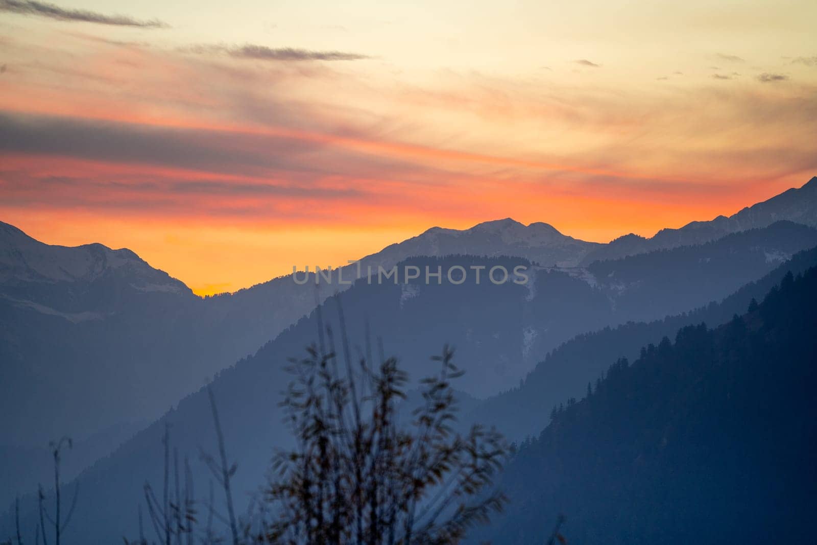 Sunrise sunset dusk dawn colors over the himalaya mountains with fog haze in distance with rich orange and red colors in manali kullu shimla by Shalinimathur