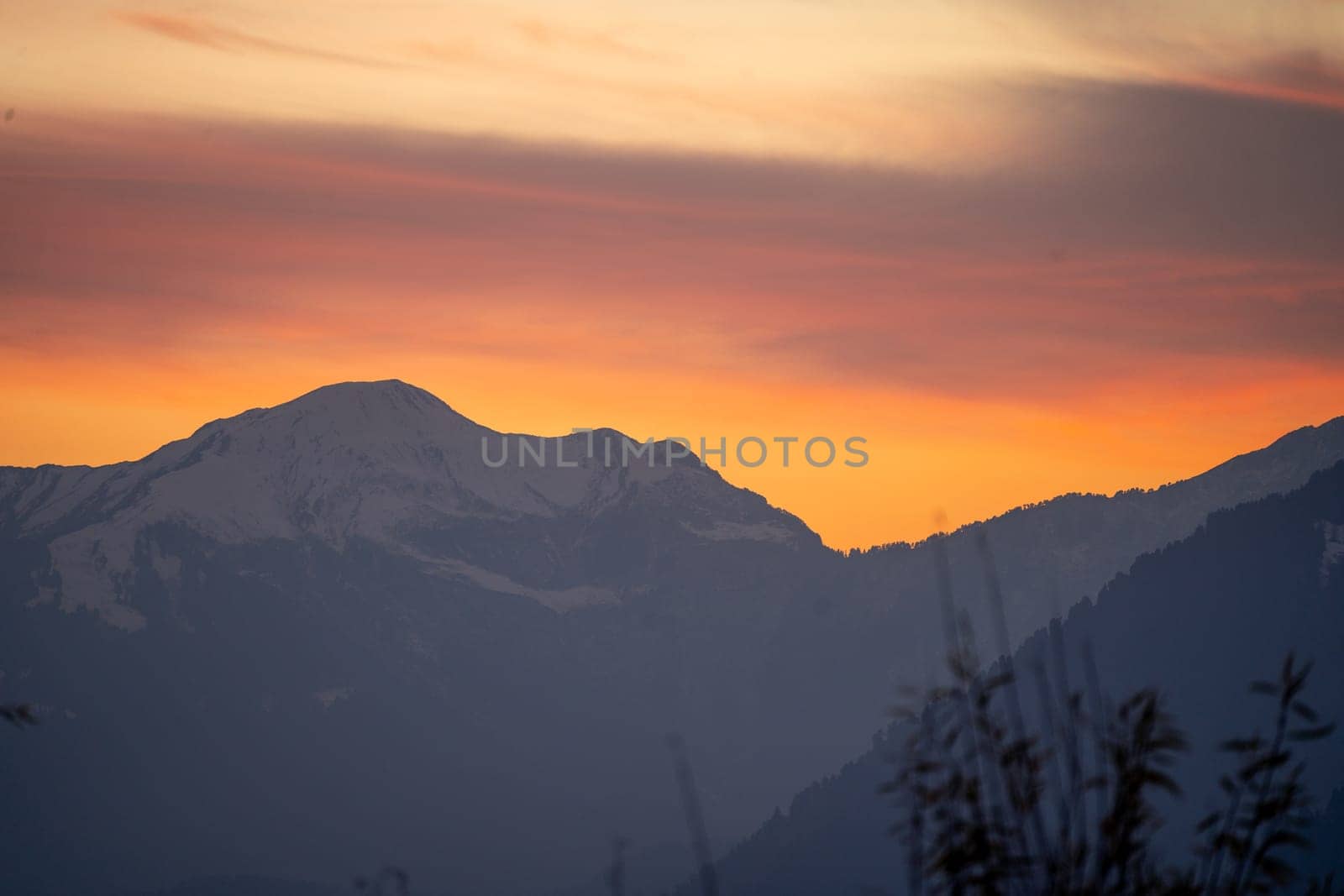 Sunrise sunset dusk dawn colors over the himalaya mountains with fog haze in distance with rich orange and red colors in manali kullu shimla in India