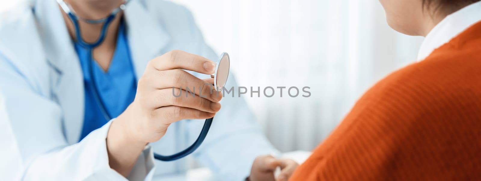 Patient attend doctor's appointment at clinic or hospital office. Doctor examining and diagnosis symptoms while checking the patient's pulse with stethoscope. Panorama Rigid
