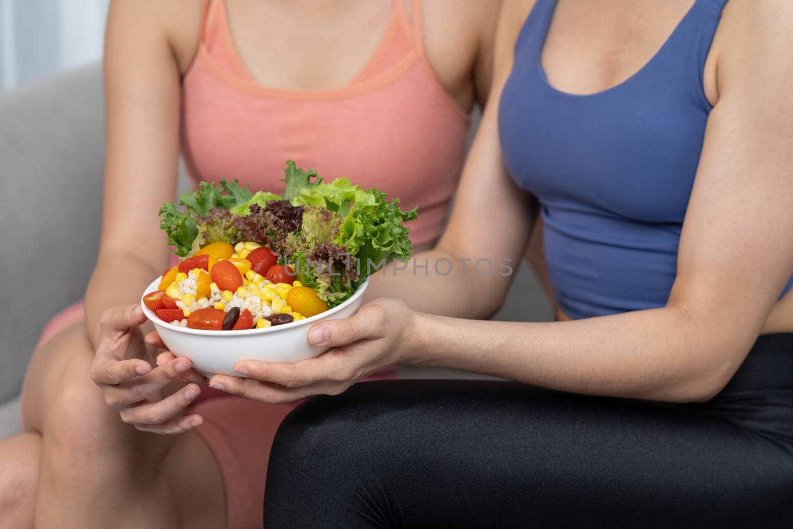 Young sporty Asian women in sportswear holding salad bowl together fill with vibrant of fruit and vegetable. Natural youthful and fit body lifestyle with balance nutrition and home exercise. Vigorous