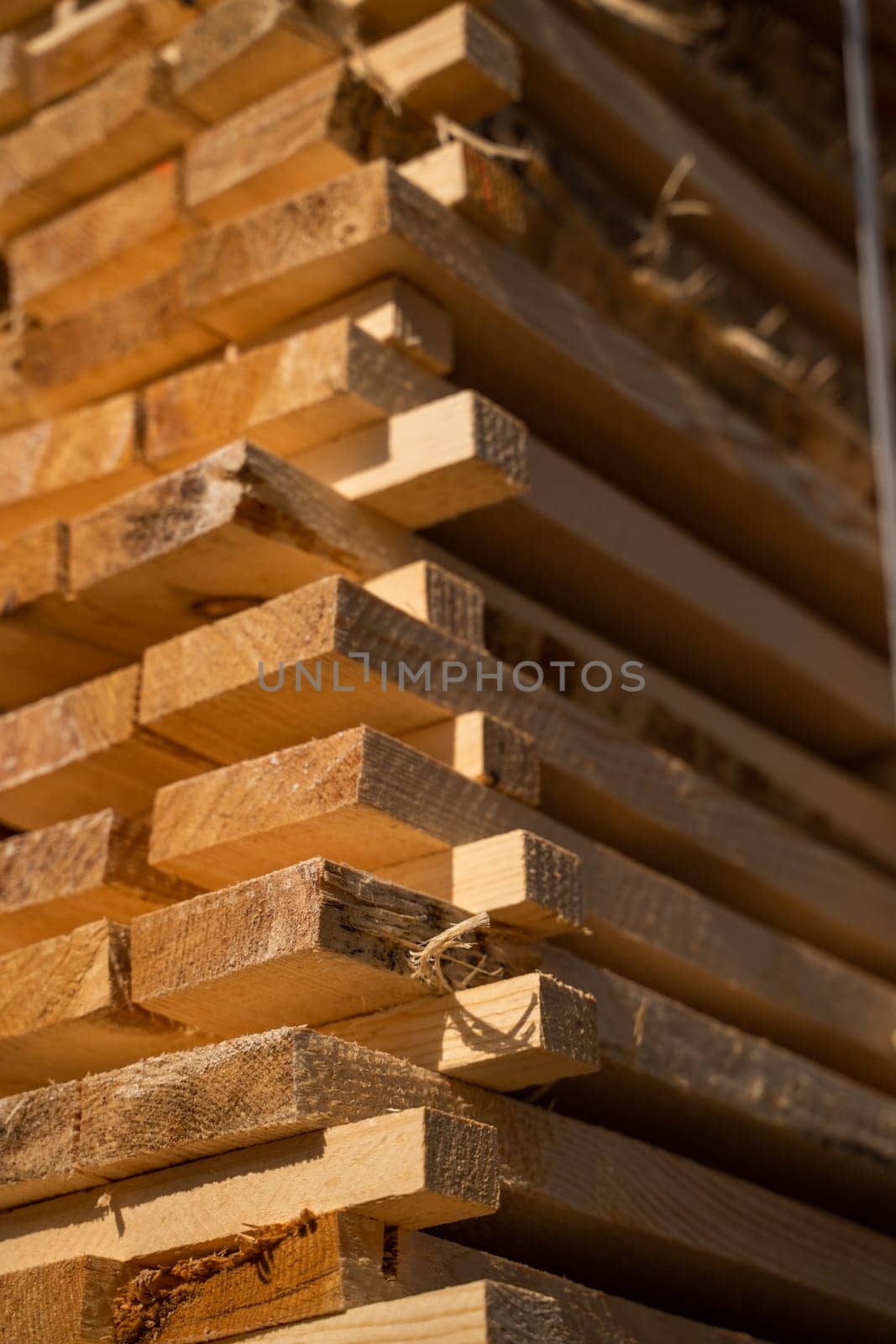 Stacked wooden planks in close-up at a outdoor lumber warehouse. Background of boards. Wood industry. by vovsht