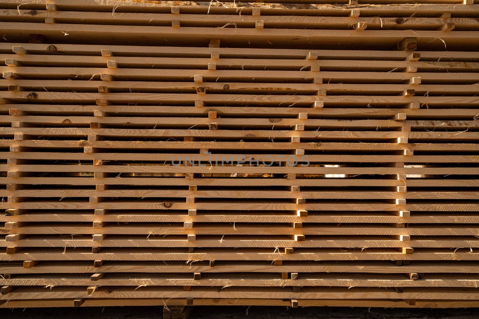 Stacked wooden boards at a outdoor lumber warehouse in a woodworking industry. Stacks with pine lumber. Folded edged board. Wood harvesting shop. by vovsht