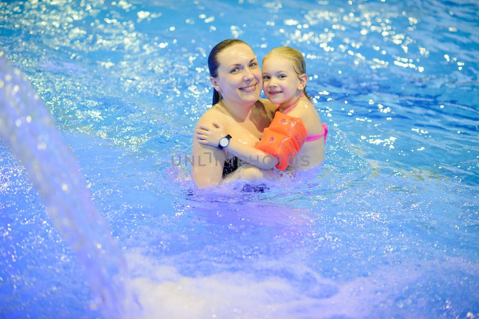 Mom and daughter are swimming in the pool with an inflatable. Healthy sports for the family.