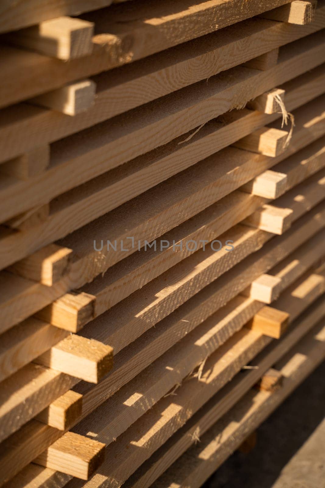 Wooden planks and beams at a outdoor lumber warehouse in a woodworking industry. Stacks with pine lumber. Folded edged board. Wood harvesting shop. by vovsht
