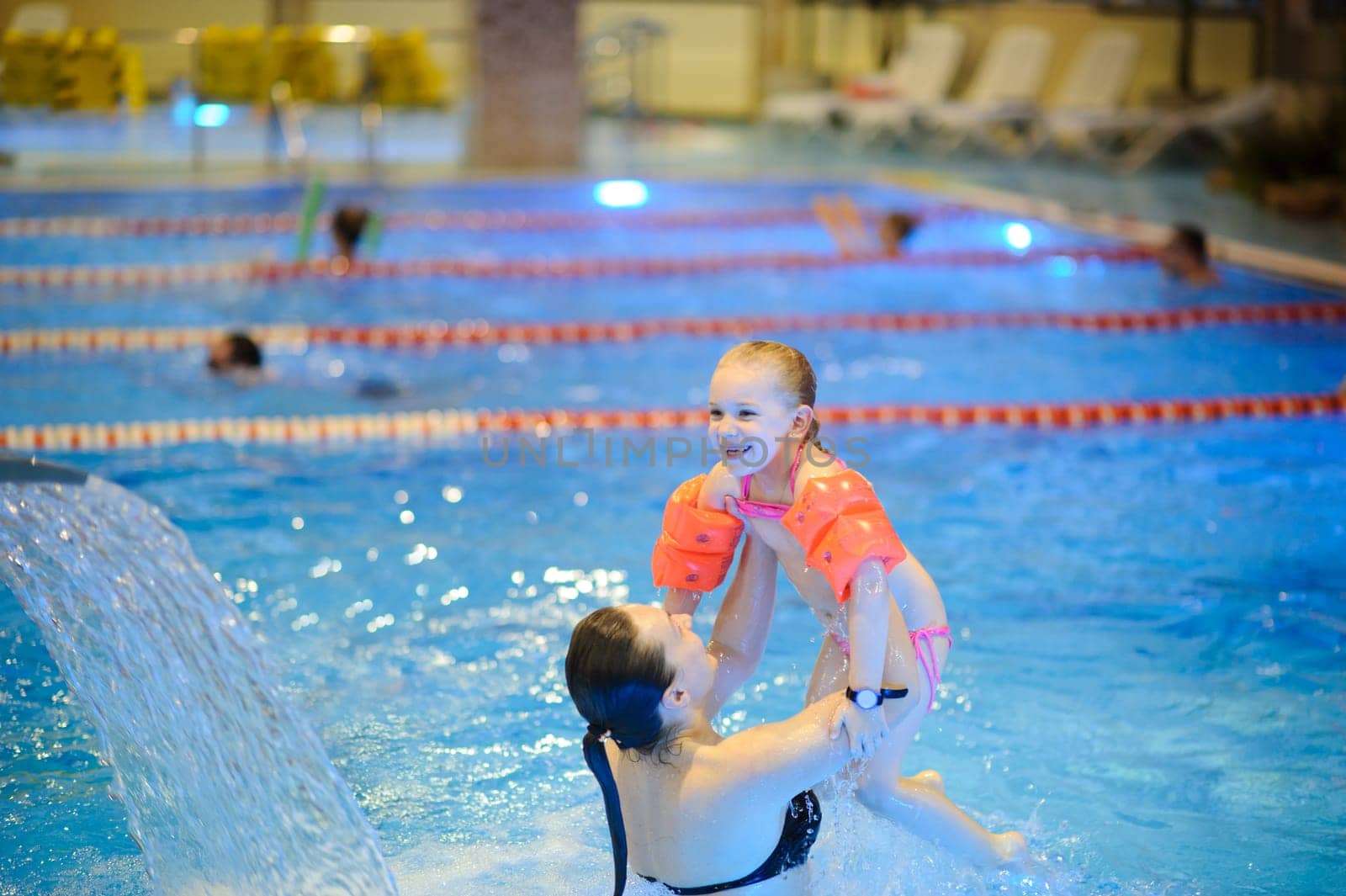 Mom and daughter are swimming in the pool with an inflatable. Healthy sports for the family.