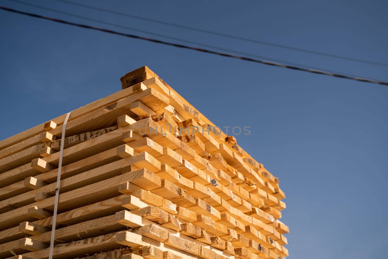Stacked raw wooden boards at a outdoor lumber warehouse. Wood industry