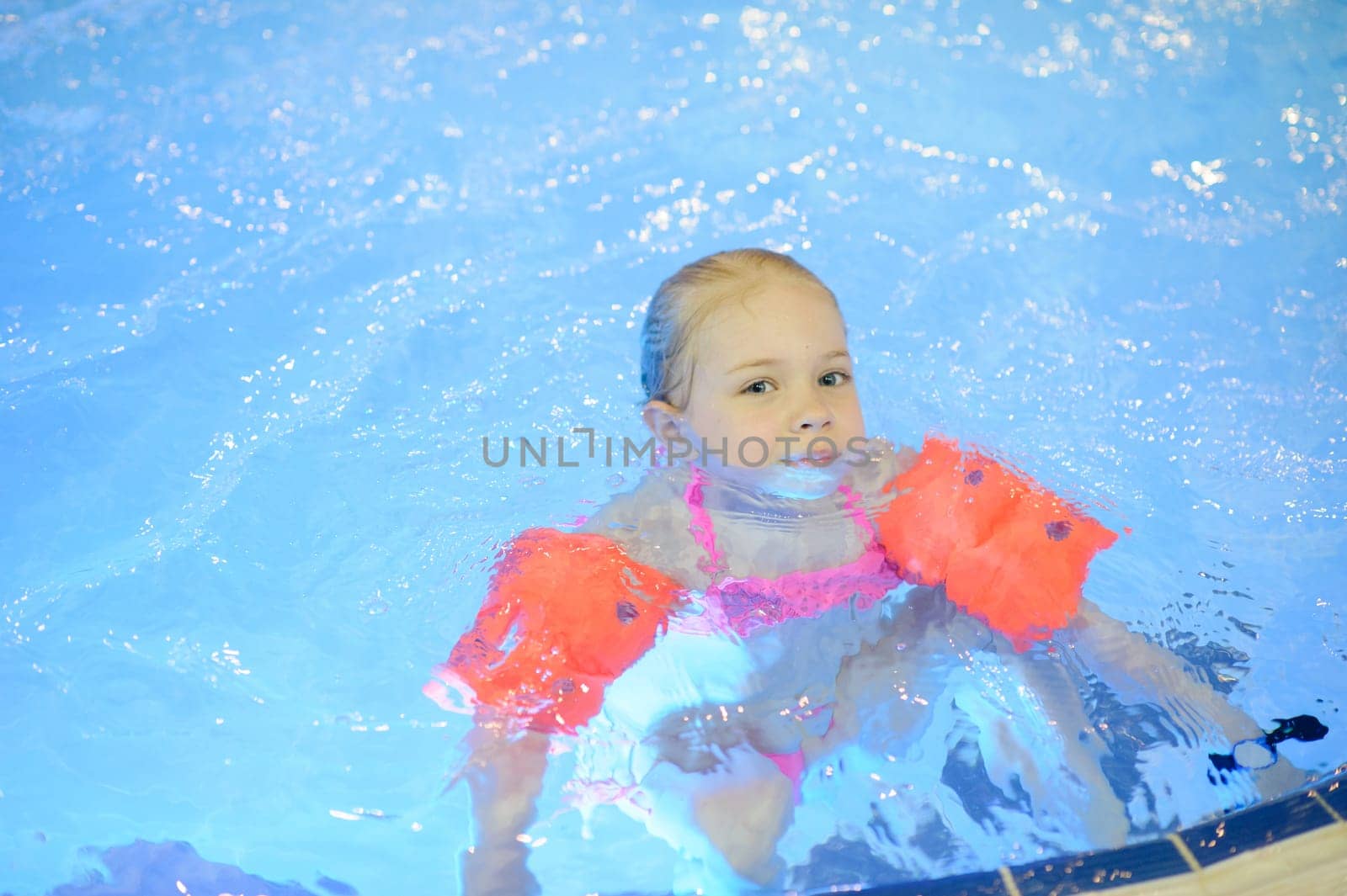 Cute girl with inflatables swimming in the pool. Healthy sport for children.