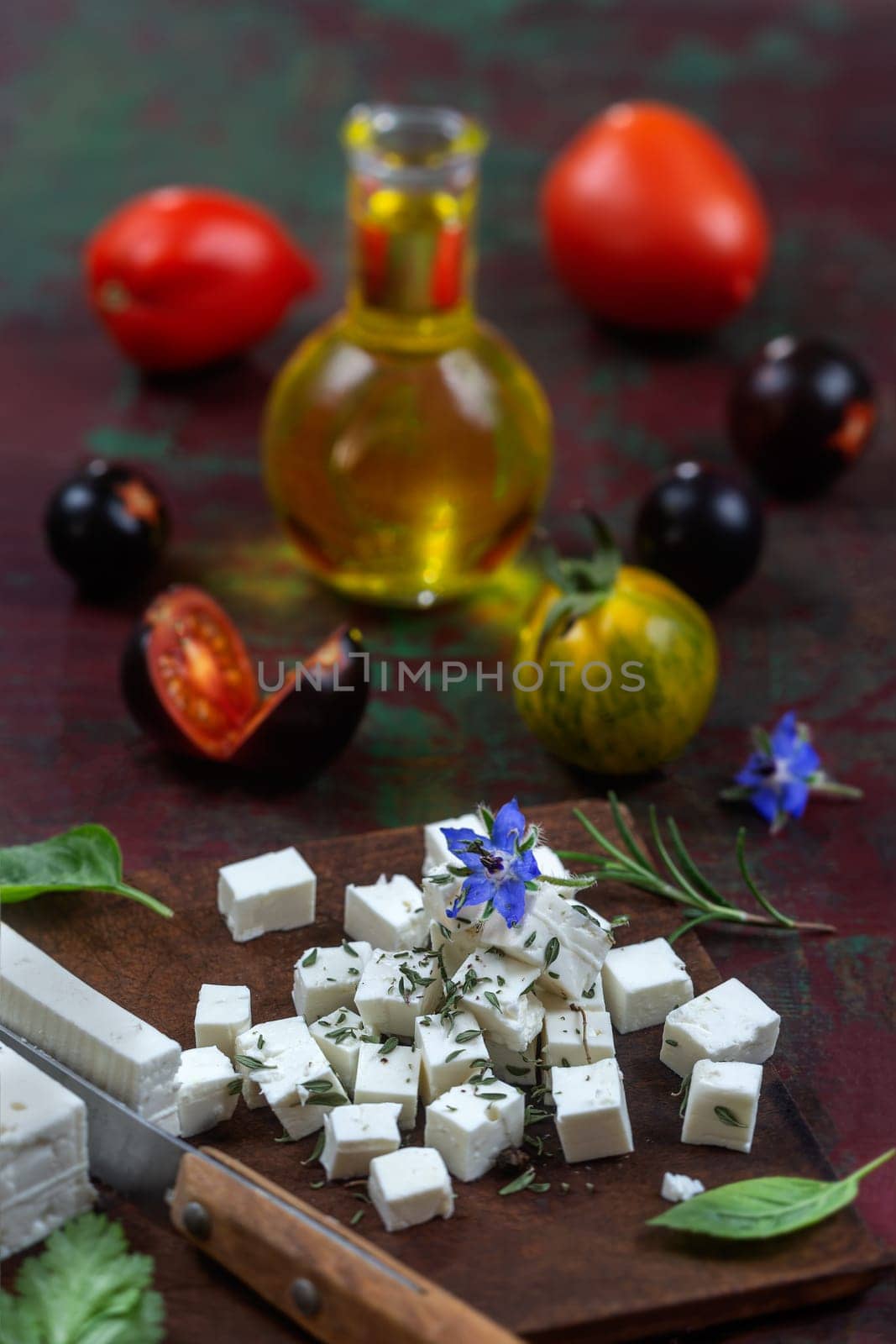 Bottle of olive oil and tomatoes with leaves feta cheese and basil isolated on a brown background by JPC-PROD