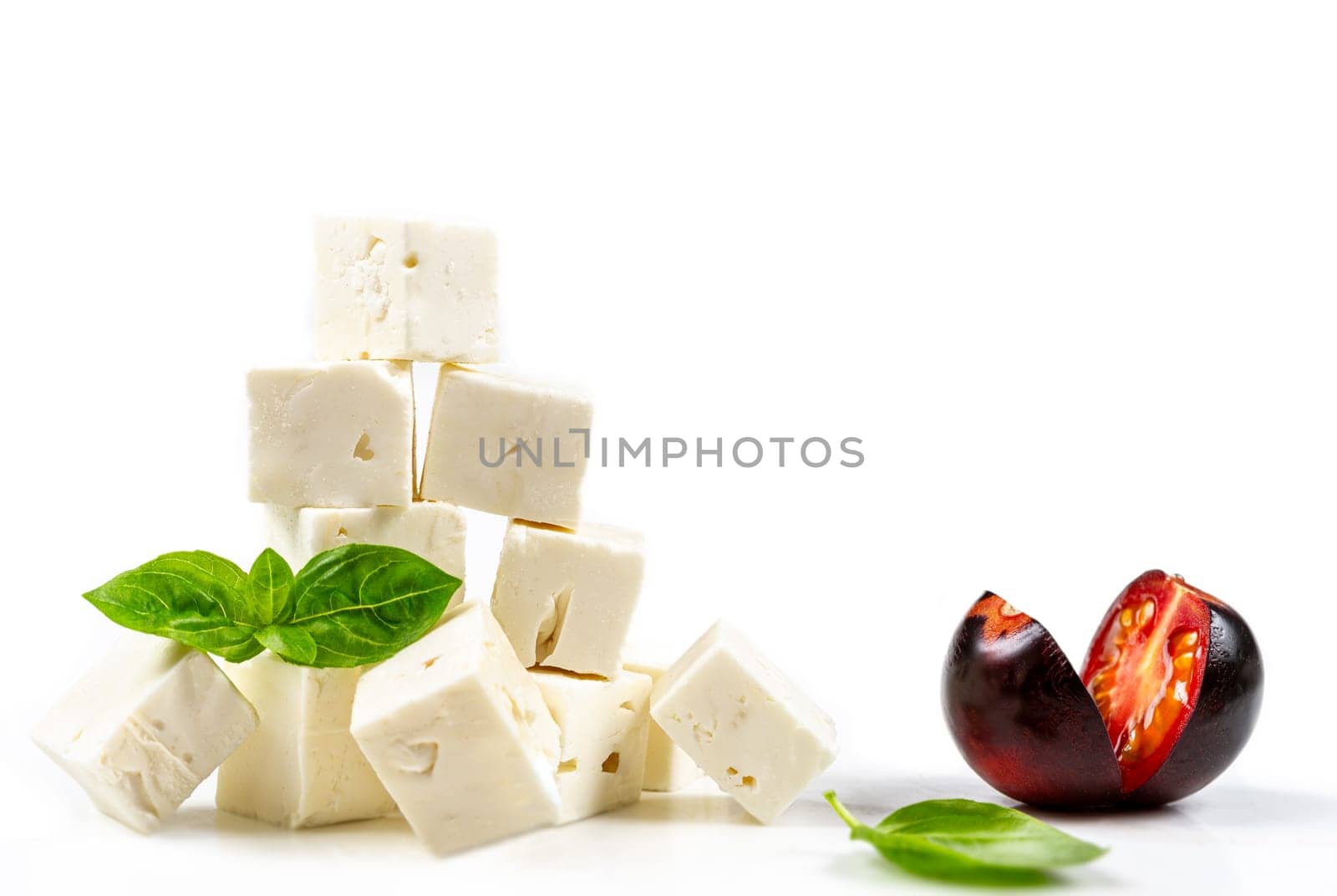 cubes Feta cheese isolated on white background clipping Heap of Feta cheese, basil leaves and tomatoes. by JPC-PROD
