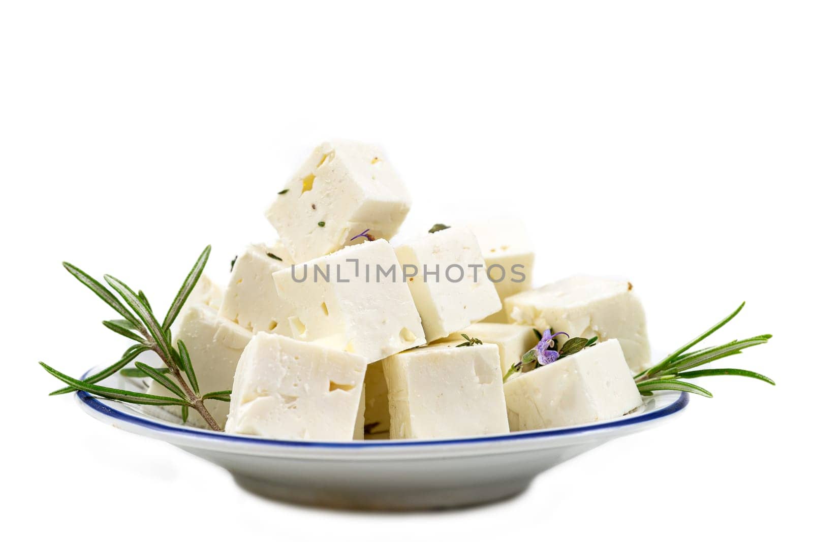 Feta cheese cubes isolated on white background with clipping path. Heap of Feta cheese, basil leaves and tomatoes.