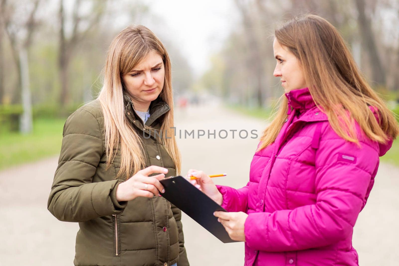 Opinion poll. A woman interviewing people, conducting survey standing outdoor.